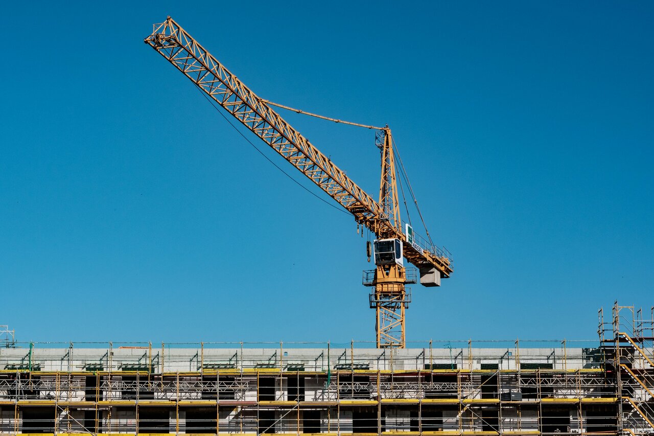 Crane assembling a modern structure, symbolizing the refactoring of cloud architecture to improve efficiency and reduce operational costs.